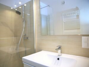 Modernes Badezimmer mit Dusche, Waschbecken und einem großen Spiegel