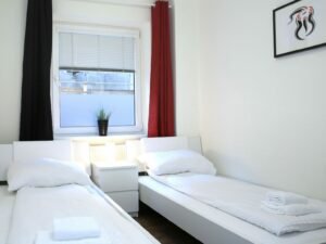 Zimmer mit zwei Einzelbetten und roten Vorhängen