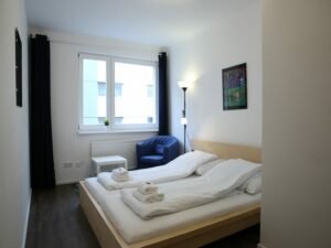 Modernes Schlafzimmer mit blauem Stuhl und hoher Lampe