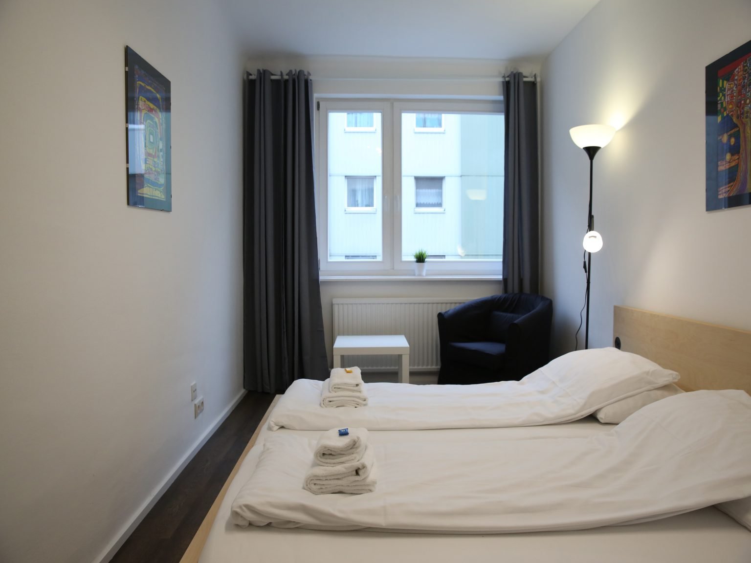 Modernes Schlafzimmer mit blauem Stuhl und hoher Lampe