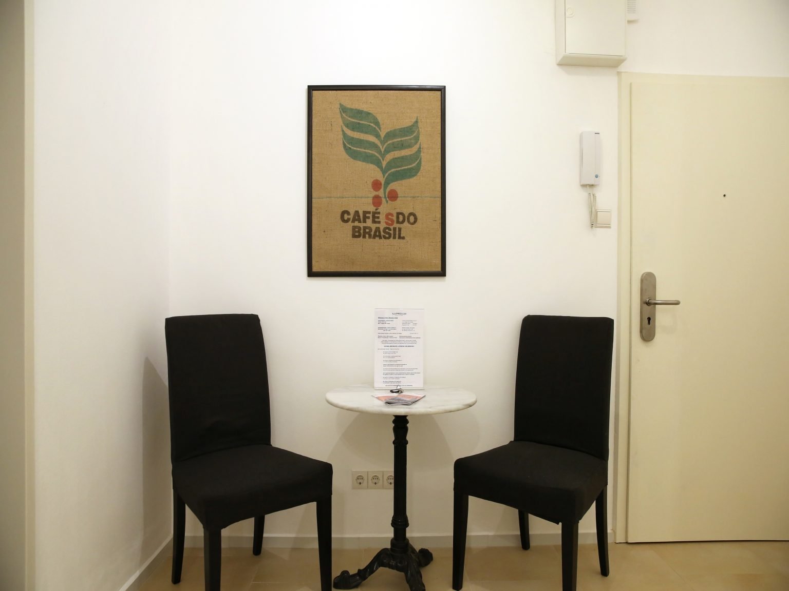 Kleine Sitzecke mit zwei schwarzen Sesseln und Infos auf dem Tisch