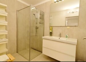 Modernes Badezimmer mit Glasdusche, großem Spiegel und neuer Einrichtung