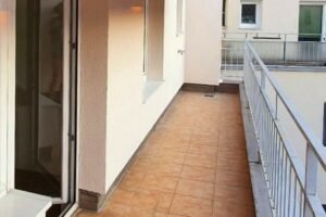 Großer Balkon mit roten Fliesen und grauem Geländer