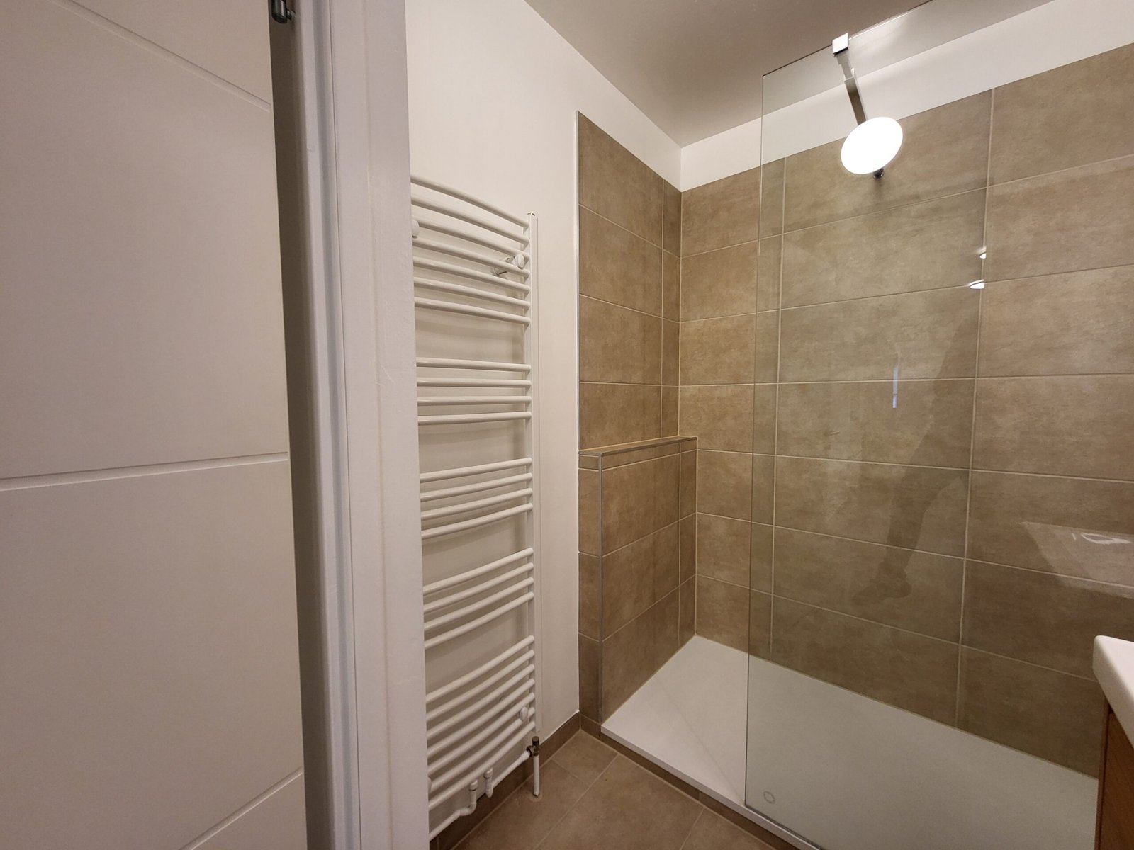 Modernes Badezimmer mit großen Fliesen und Heizkörper