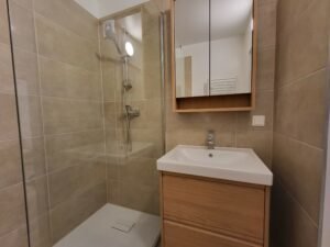 Modernes Badezimmer mit Holzmöbeln und einer Glasdusche