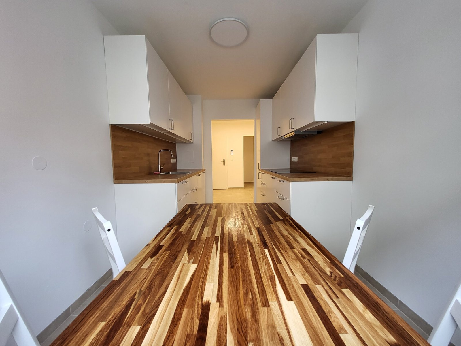 Moderne, weiße Küche mit großer Holzplatte und Essbereich