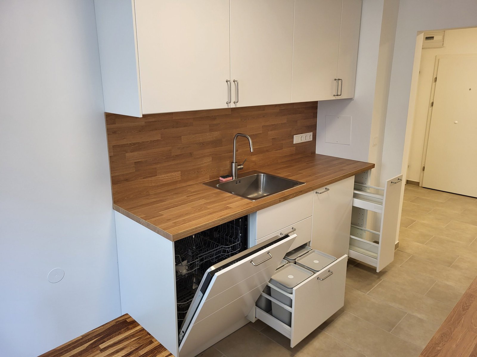 Moderne, weiße Küche mit Holzplatte und Geschirrspüler