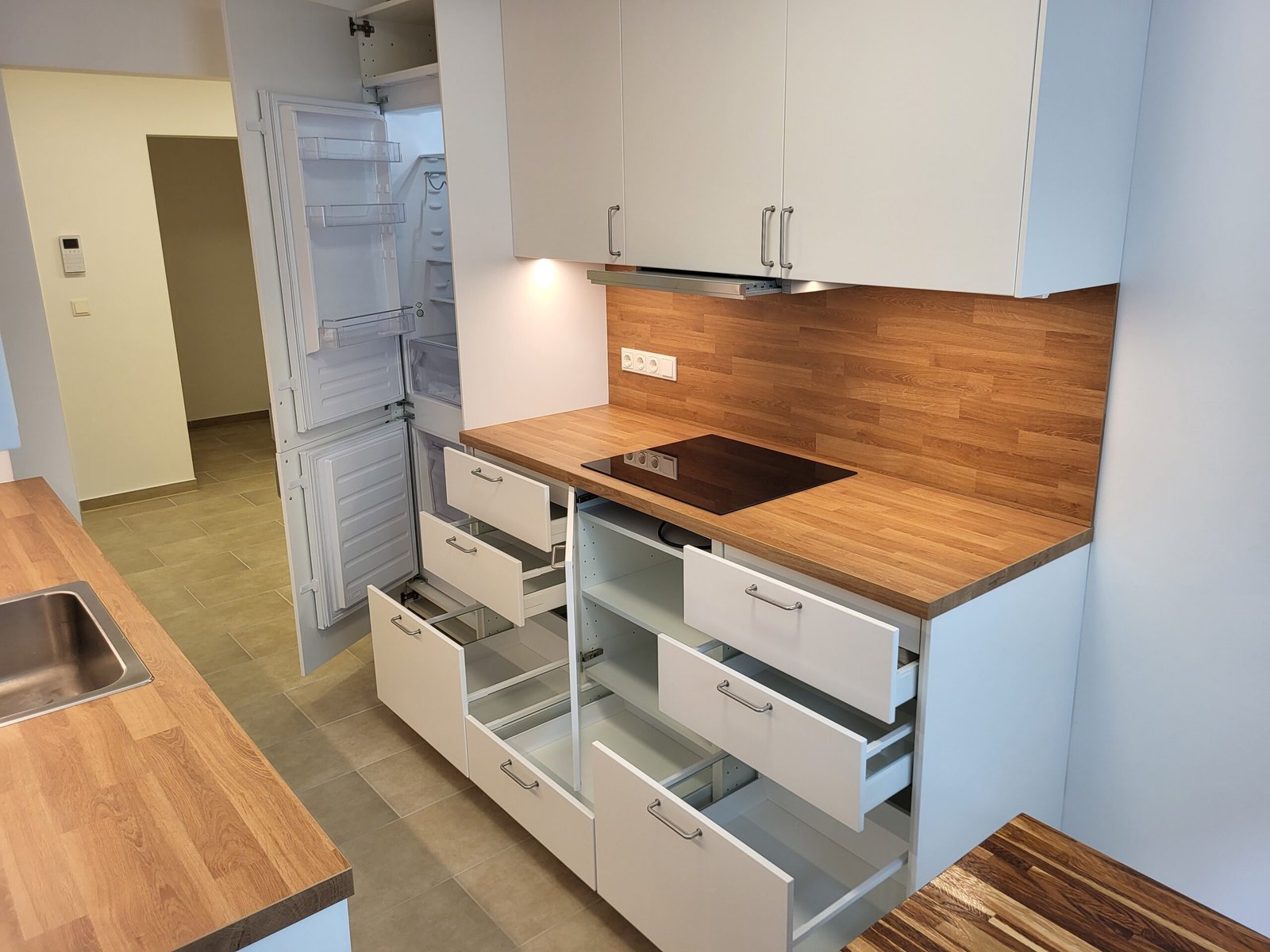 Moderne, weiße Küche mit Holzplatte und viel Stauraum